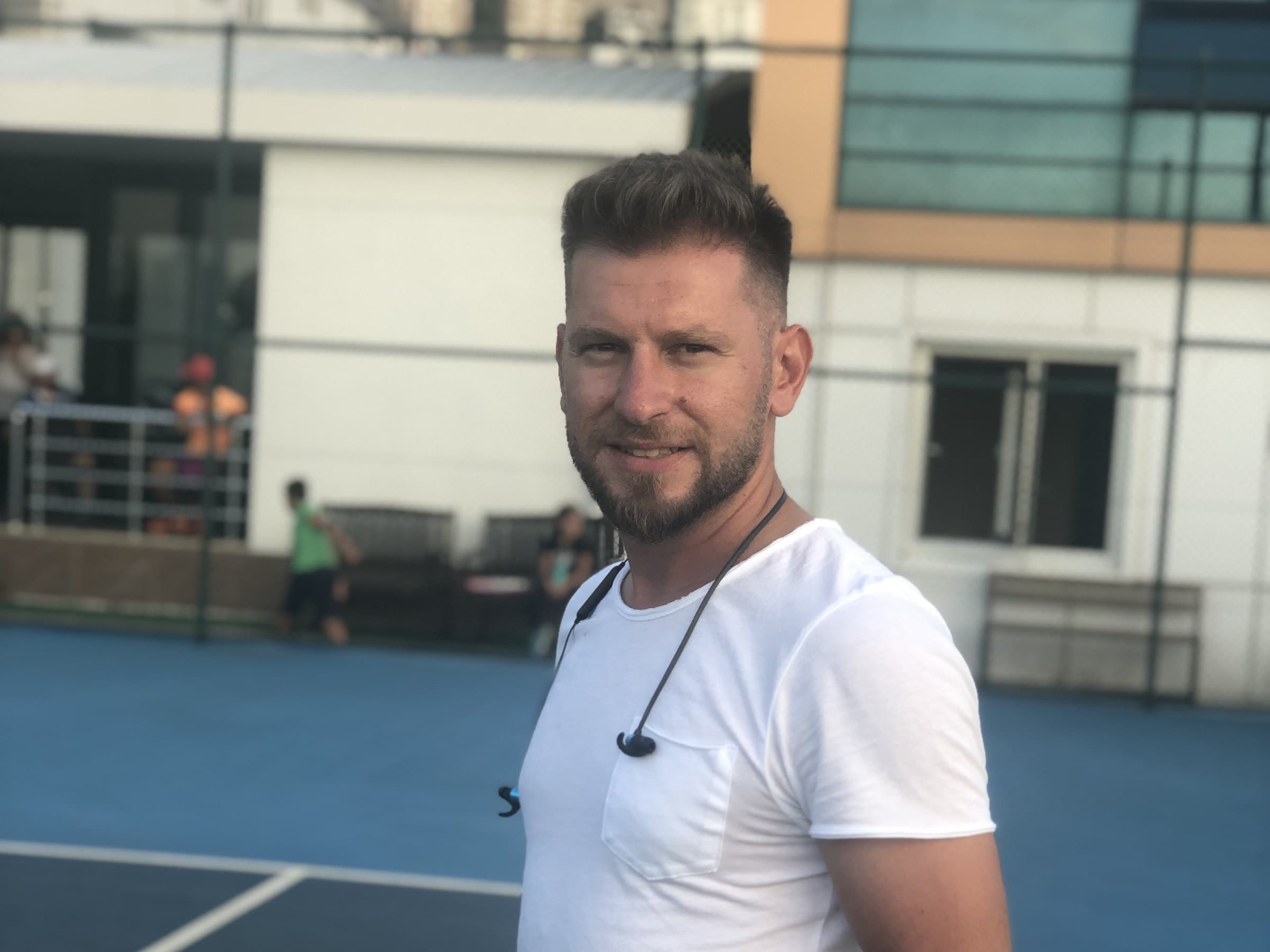 Ali Faik Hacıömeroğlu — elinde raket ve tenis toplarıyla kortta duran Trabzon Tenis Kulübü antrenörü